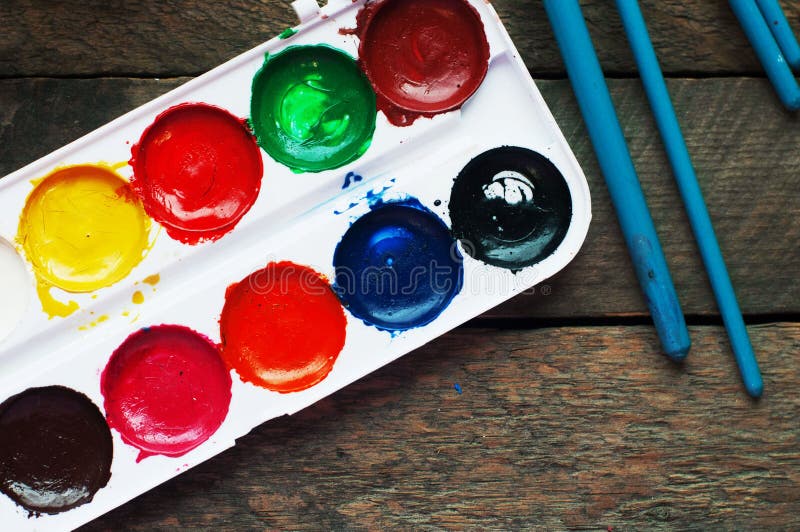 Art of Painting. Paint buckets on wood background. Different paint colors painting on wooden background. Painting set: brushes, paints, crayons, chalk, watercolor, acrylic paint on a wooden background