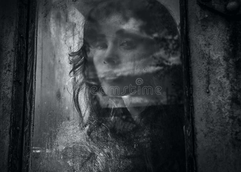 Art portrait of a beautiful young spooky woman, looks through grunge styled window.