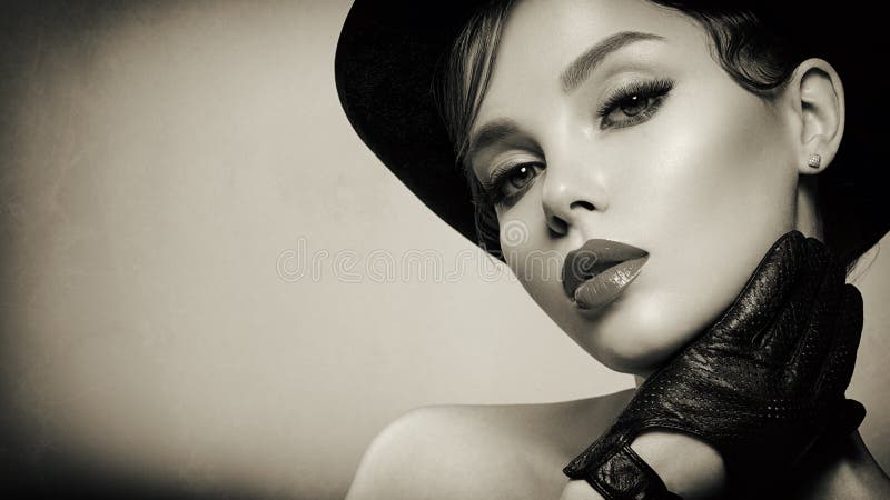 Art portrait of beautiful young woman  in a black hat. Stylized black and white portrait. Attractive model with a black gloves at
