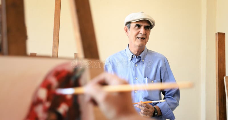 Art School With Teacher Talking ao estudante Painting fotos de stock royalty free Art School With Teacher Talking ao estudante Painting fotos de stock royalty free