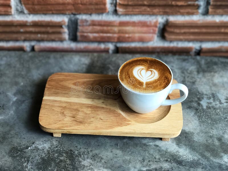 Arte de flautín del latte del amor del corazón en la taza blanca en piso de madera de la bandeja y del cemento con la luz natural imagenes de archivo Arte de flautín del latte del amor del corazón en la taza blanca en piso de madera de la bandeja y del cemento con la luz natural imagenes de archivo