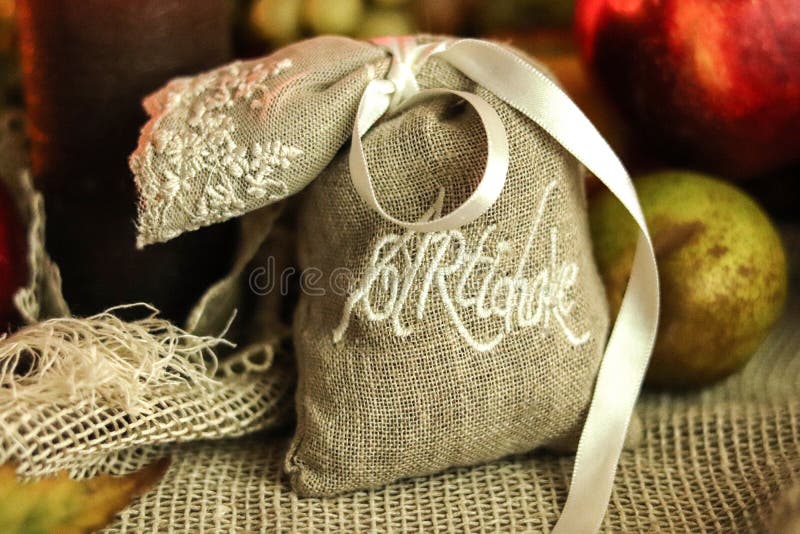 Artichoke herbs in a small cloth bag pouch with a white lace ribbon and fruits on sackcloth background still life. stock image Artichoke herbs in a small cloth bag pouch with a white lace ribbon and fruits on sackcloth background still life. stock image