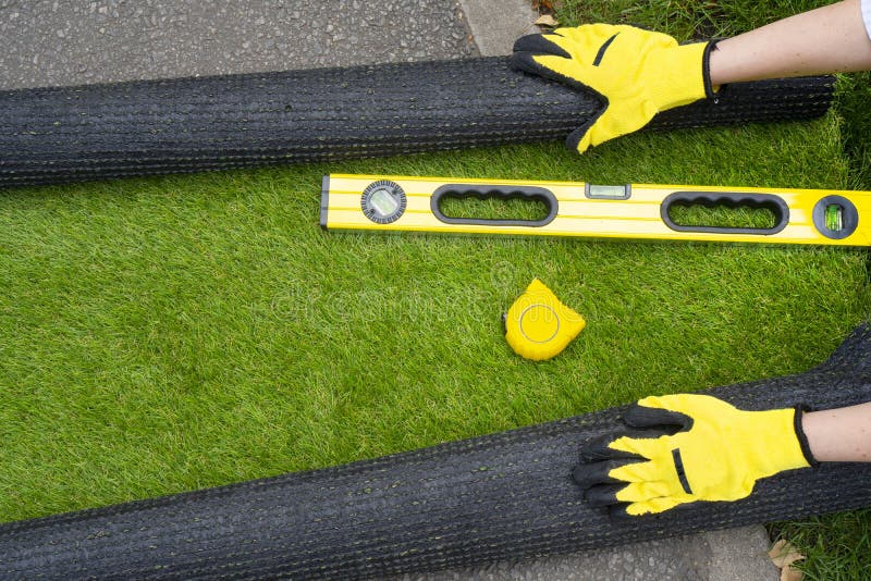 Artificial grass roll and tools in female hands. stock images