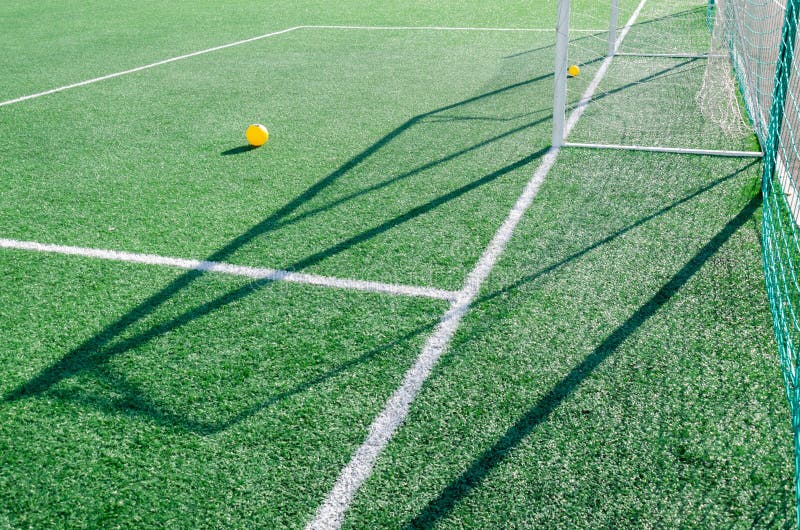 Artificial grass, white lines and soccer goal on a sunny day. Yellow balls on the grass stock photography Artificial grass, white lines and soccer goal on a sunny day. Yellow balls on the grass stock photography