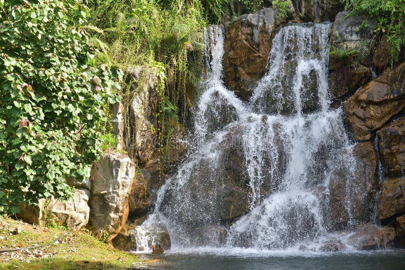 A photo taken on an artificial man made low waterfall under the midday sun. Man made waterfall stock images, royalty-free photos and pictures