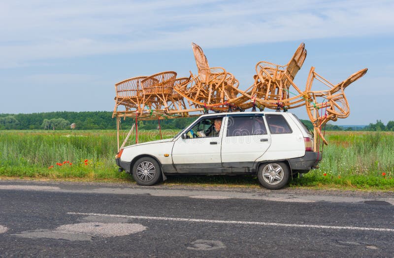 Artigiano che ha una breve pausa mentre lavoro in vimini di trasporto su un tetto di piccola automobile fotografie stock libere da diritti Artigiano che ha una breve pausa mentre lavoro in vimini di trasporto su un tetto di piccola automobile fotografie stock libere da diritti