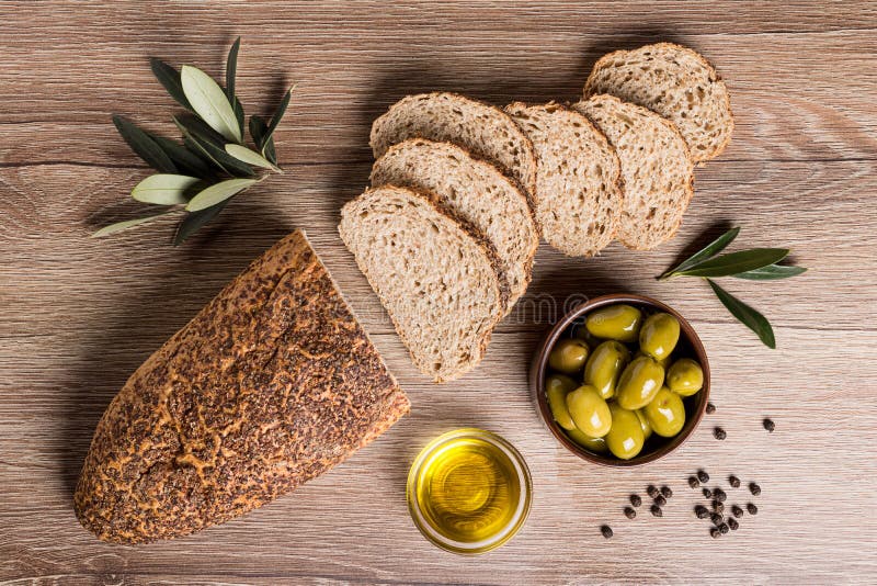 Artisanaal brood met olijven en olijfolie op een houten lijst stock fotografie Artisanaal brood met olijven en olijfolie op een houten lijst stock fotografie