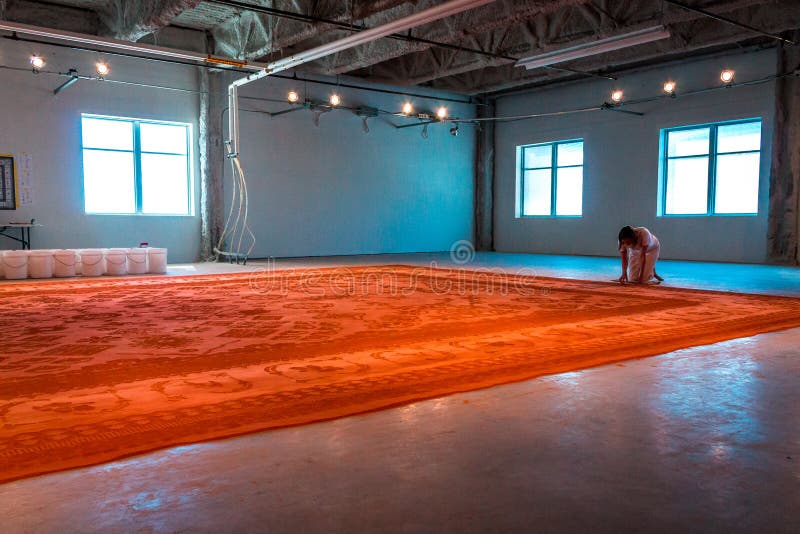 Artist creating a red dirt rug with stamps at Artprize 9 in Grand Rapids Michigan stock photography Artist creating a red dirt rug with stamps at Artprize 9 in Grand Rapids Michigan stock photography