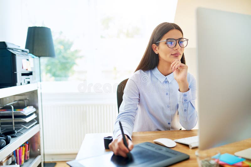 Digital artist drawing on computer with stylus and tablet next to her in small office. Computer editing stock images, royalty-free photos and pictures