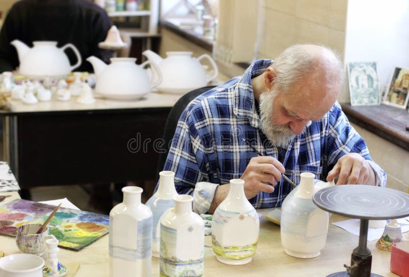 Más viejo esmalte artista la pintura cerámica sobre el su lugar de trabajo en arte cerámica taller.