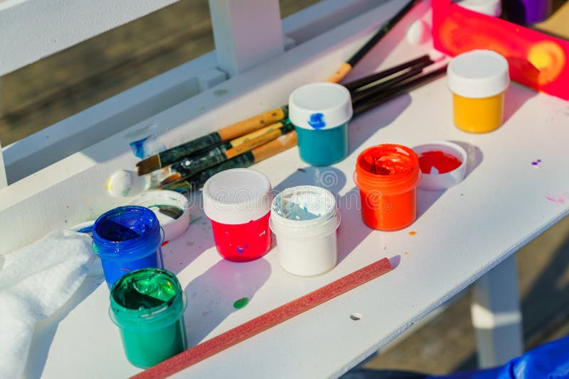 Artist`s work place. Open multicolored gouache, paint brushes and pencil on white table royalty free stock photo Artist`s work place. Open multicolored gouache, paint brushes and pencil on white table royalty free stock photo