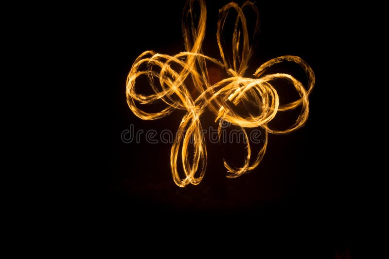 The Artist Shows a Fire Show at Night Spinning Torches, Circles of Fire and Loops Stock Photo
