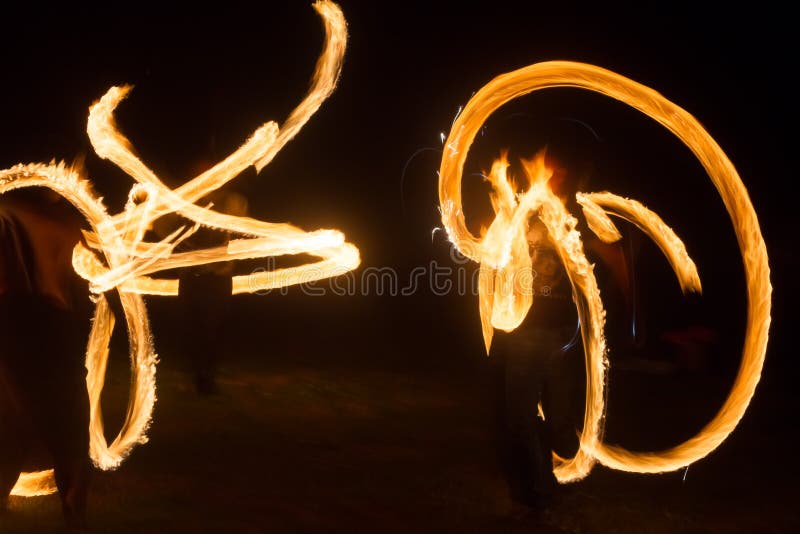 The Artist Shows a Fire Show at Night Spinning Torches, Circles of Fire and Loops Stock Photo