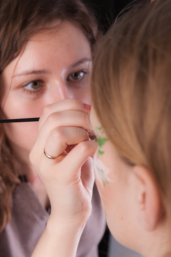 An artist making the flower tattoo on the face of