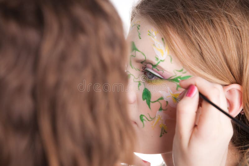 An artist making a picture on the face of her model