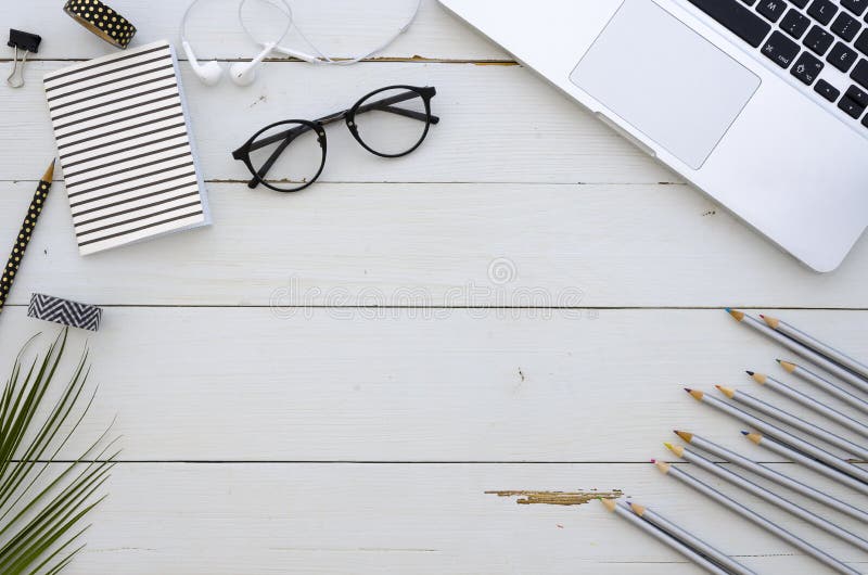 Artist workspace with laptop, glasses, colored pencils and white earplugs . Hand lettering inspiration quote. Hipster