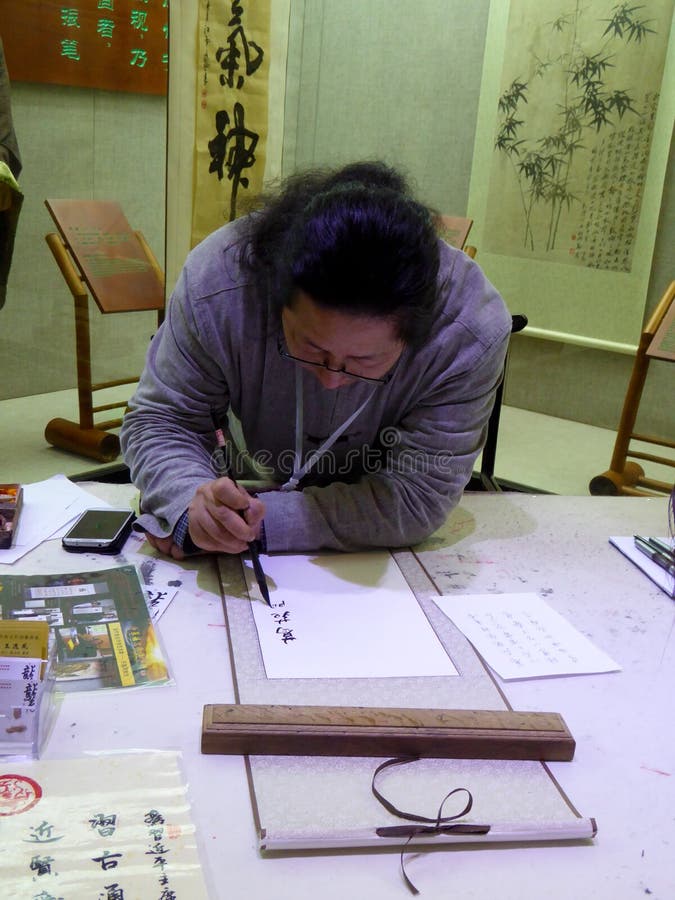 A male artist writing calligraphy carefully on the desk in liyang city jiangsu province China. A male artist writing calligraphy carefully on the desk in liyang city jiangsu province China.