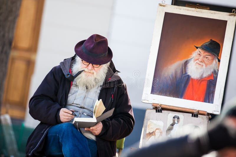 Artista barbuto senior che lavora al Place du Tertre famoso nel Montmartre fotografia stock Artista barbuto senior che lavora al Place du Tertre famoso nel Montmartre fotografia stock