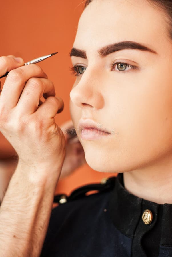 Artista de maquillaje que hace maquillaje de una chica joven hermosa en el estudio imagen de archivo libre de regalías Artista de maquillaje que hace maquillaje de una chica joven hermosa en el estudio imagen de archivo libre de regalías