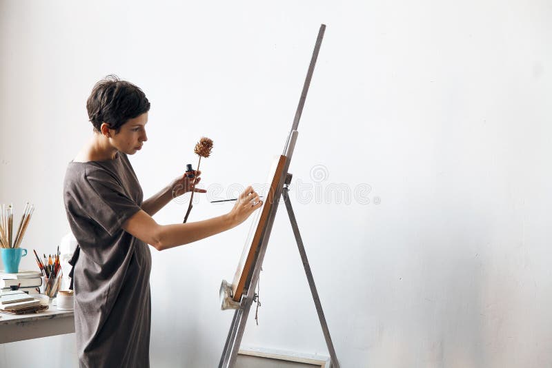 Artista femminile nel suo studio bianco spazioso che lavora con la pittura dell'acquerello immagine stock