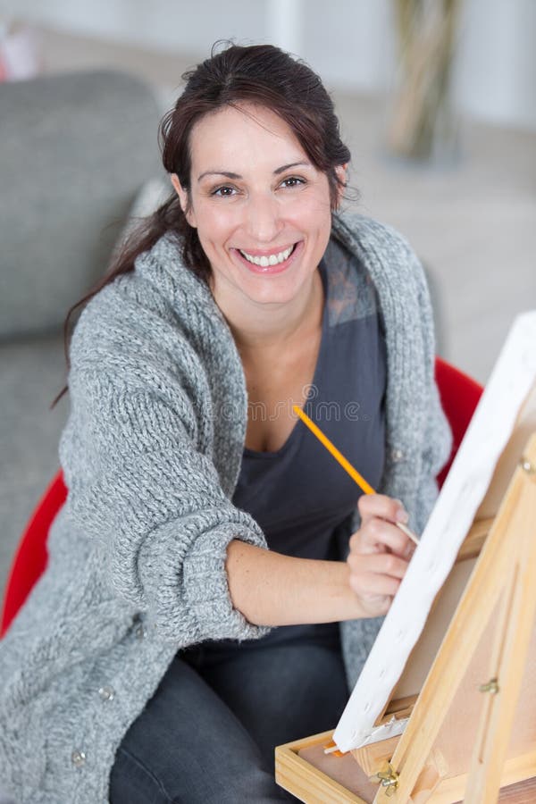 Artista femminile Working On Painting nello studio luminoso di luce del giorno fotografie stock libere da diritti Artista femminile Working On Painting nello studio luminoso di luce del giorno fotografie stock libere da diritti