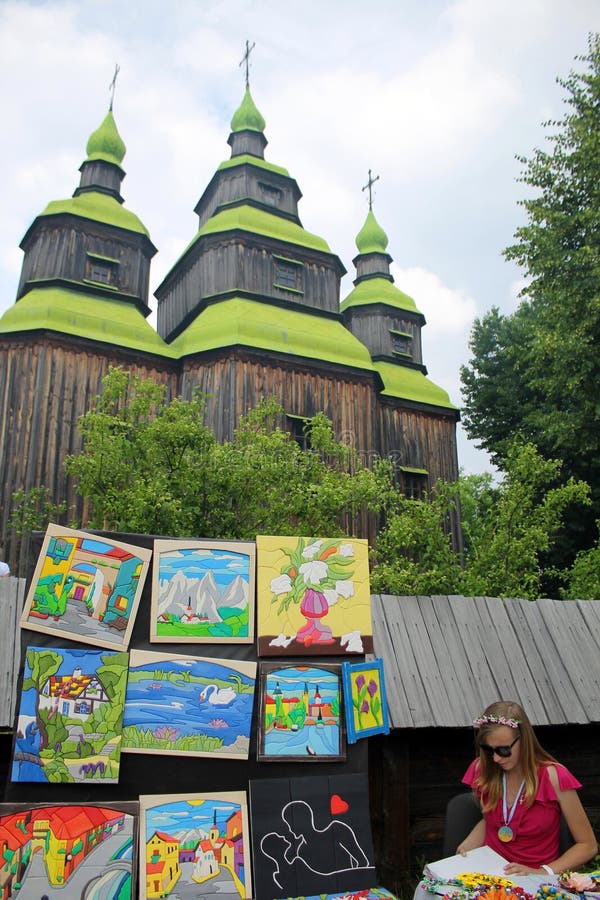 Artista ucraniano cerca de la iglesia ortodoxa de madera en el museo Pirogovo, foto de archivo Artista ucraniano cerca de la iglesia ortodoxa de madera en el museo Pirogovo, foto de archivo
