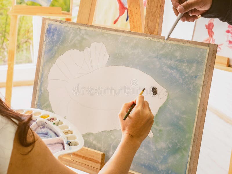 Artrist asiático de las mujeres que pinta los pescados en sala de clase mientras que su enseñanza y profesor particular del profe fotos de archivo libres de regalías Artrist asiático de las mujeres que pinta los pescados en sala de clase mientras que su enseñanza y profesor particular del profe fotos de archivo libres de regalías