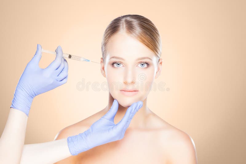 Arts die in een mooi gezicht van een jonge vrouw inspuiten Plastic s stock afbeelding Arts die in een mooi gezicht van een jonge vrouw inspuiten Plastic s stock afbeelding
