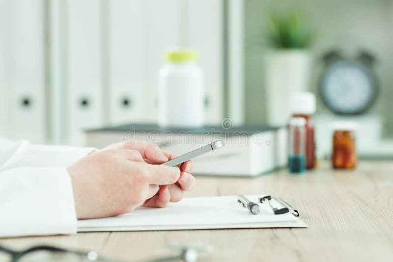 Arts die smartphone in medisch bureau gebruiken royalty-vrije stock afbeeldingen Arts die smartphone in medisch bureau gebruiken royalty-vrije stock afbeeldingen