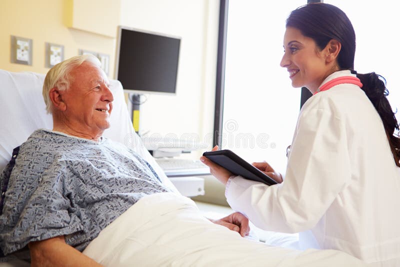 Doctor With Digital Tablet Talking To Patient In Hospital Smiling At Each Other. Doctor With Digital Tablet Talking To Patient In Hospital Smiling At Each Other