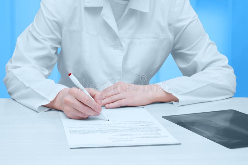 Arts in een witte laag bij de lijst en de tekens een x-ray examen Close-up royalty-vrije stock afbeeldingen Arts in een witte laag bij de lijst en de tekens een x-ray examen Close-up royalty-vrije stock afbeeldingen