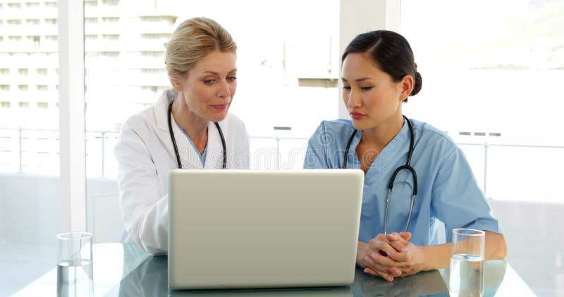 Arts en verpleegster die over een dossier op laptop gaan