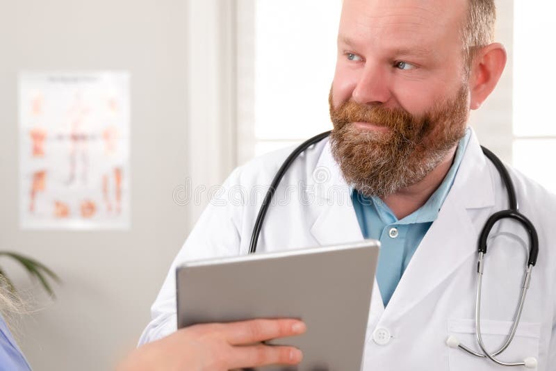 Artsen die rapport over een pati?nt bespreken bij tabletcomputer in het ziekenhuis stock afbeelding Artsen die rapport over een pati?nt bespreken bij tabletcomputer in het ziekenhuis stock afbeelding