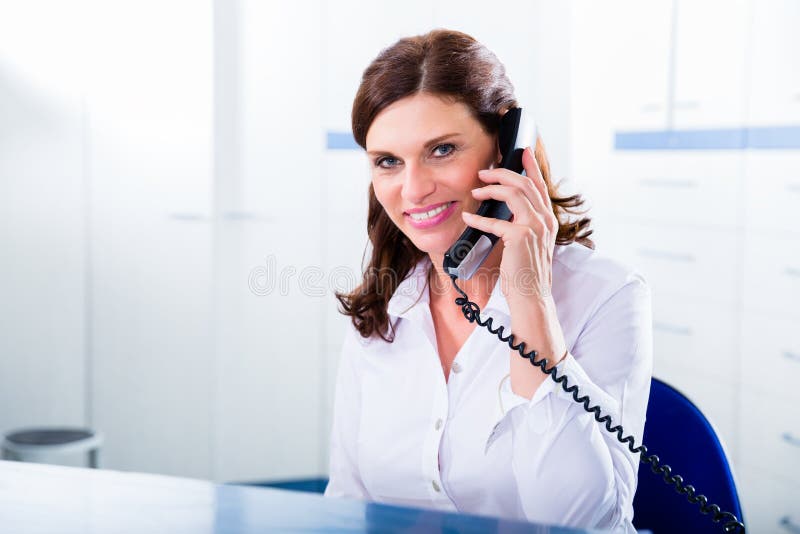 Artsenverpleegster met telefoon vooraan bureau royalty-vrije stock foto's Artsenverpleegster met telefoon vooraan bureau royalty-vrije stock foto's