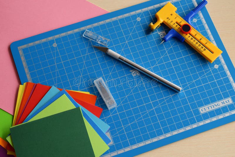 Artwork equipment and tools for paper cut - cutting knife, sharp box cutter, blue cutting plate, origami paper. Modern 3d origami royalty free stock photo Artwork equipment and tools for paper cut - cutting knife, sharp box cutter, blue cutting plate, origami paper. Modern 3d origami royalty free stock photo