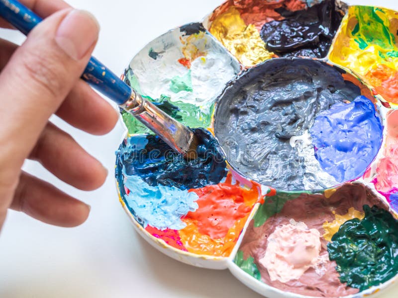 Artysta ręka miesza akrylowej farby kolor z muśnięciem w plastikowej białej sztuki palecie fotografia stock Artysta ręka miesza akrylowej farby kolor z muśnięciem w plastikowej białej sztuki palecie fotografia stock
