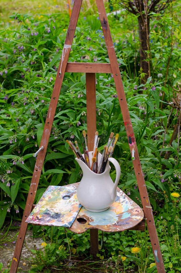 Artystyczna rocznik sztaluga, paintbrushes i stara drewniana paleta, fotografia stock Artystyczna rocznik sztaluga, paintbrushes i stara drewniana paleta, fotografia stock