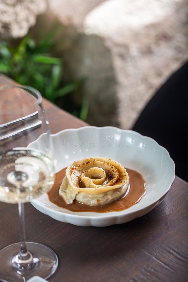 Artă culinară în prezentarea desertului care prezintă o ruladă delicată de patiserie cu sos bogat și sticlă elegantă de vin stock photography