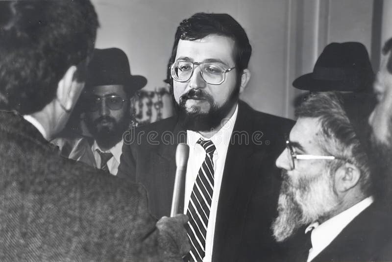 Newly-installed Interior Minister, Arye Deri, takes a question from a member of the press after a meeting with his Shas Party political faction in the Knesset in December, 1988.  Deri became the youngest government minister at 29, even though he had not formally run for the position in an election.  In any case, a few years later he ran and won a Knesset Parliament seat.  But in 1999 he was convicted of fraud, bribery, and breech of trust, and served 2 years in prison.  In 2013 he ran again and won.  In 2022, he was convicted of tax crimes.  The Israel Supreme Court said this disqualified him for a seat in the Netanyahu government in January, 2023.  His fate remains uncertain.  Shas is Sephardic Orthodox religious party with a large working class constituency of Moroccan Jewish descent. Newly-installed Interior Minister, Arye Deri, takes a question from a member of the press after a meeting with his Shas Party political faction in the Knesset in December, 1988.  Deri became the youngest government minister at 29, even though he had not formally run for the position in an election.  In any case, a few years later he ran and won a Knesset Parliament seat.  But in 1999 he was convicted of fraud, bribery, and breech of trust, and served 2 years in prison.  In 2013 he ran again and won.  In 2022, he was convicted of tax crimes.  The Israel Supreme Court said this disqualified him for a seat in the Netanyahu government in January, 2023.  His fate remains uncertain.  Shas is Sephardic Orthodox religious party with a large working class constituency of Moroccan Jewish descent.