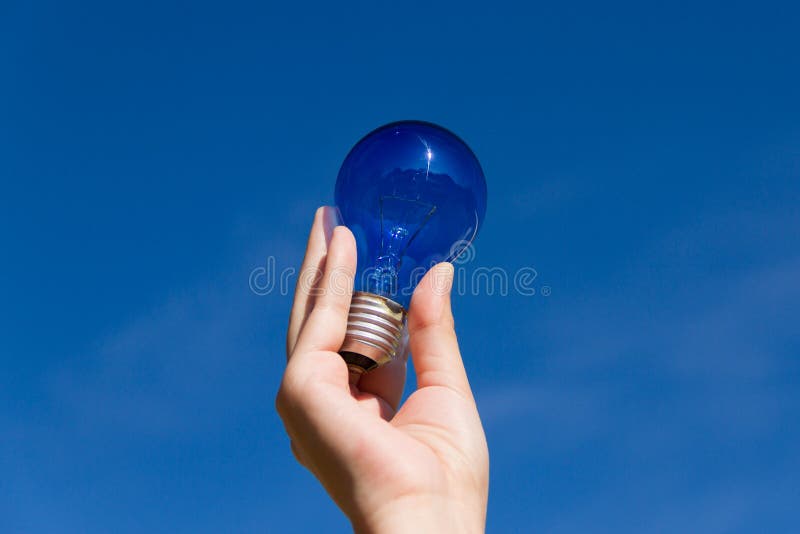 Hand holds a light bulb and a blue sky. Hand holds a light bulb and a blue sky