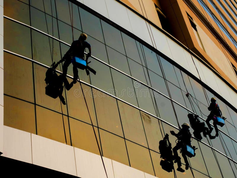 Washers wash the windows mirror of skyscraper silhouette shot. Washers wash the windows mirror of skyscraper silhouette shot.