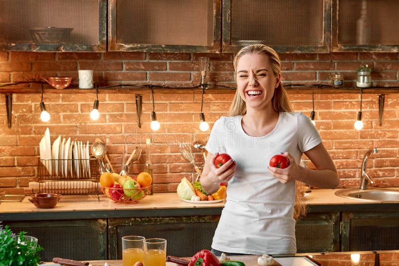 As boas escolhas do alimento são bons investimentos Jovem mulher feliz que cozinha vegetais na cozinha moderna Interior acolhedor foto de stock royalty free As boas escolhas do alimento são bons investimentos Jovem mulher feliz que cozinha vegetais na cozinha moderna Interior acolhedor foto de stock royalty free