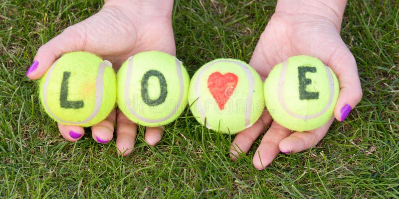 As bolas de tênis com amor da palavra e coração do amor guardaram pela mulher