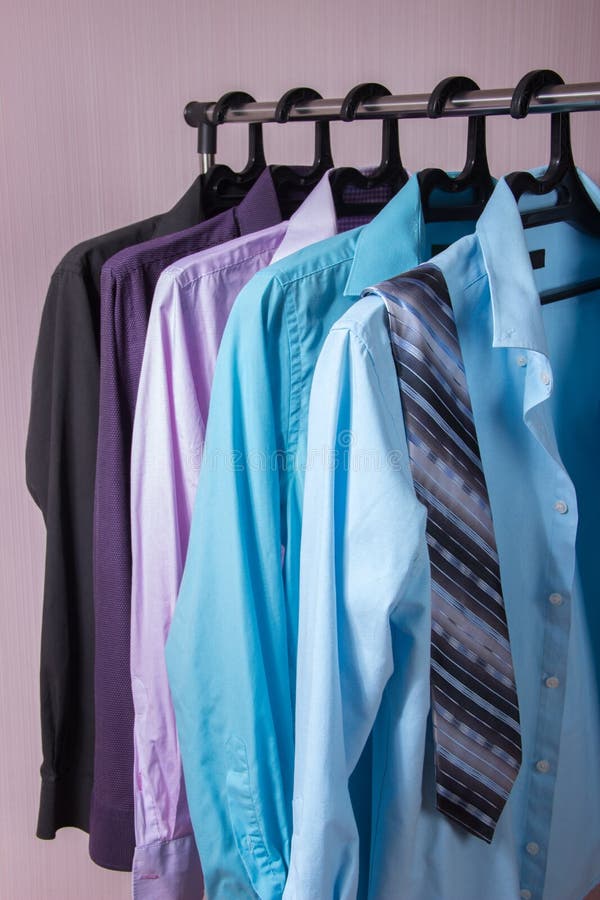 As camisas de homens coloridos que penduram em ganchos fotos de stock As camisas de homens coloridos que penduram em ganchos fotos de stock