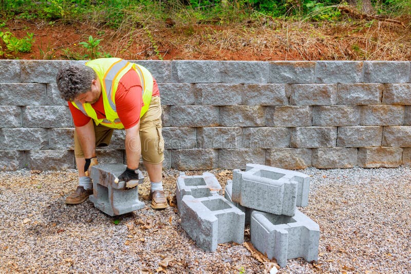 Construction Worker is Mounting a Retaining Wall Using Concrete Blocks