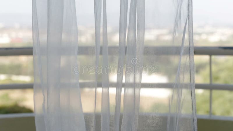 As cortinas movem-se do vento com uma vista da janela