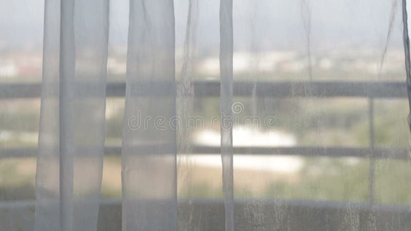 As cortinas movem-se do vento com uma vista da janela