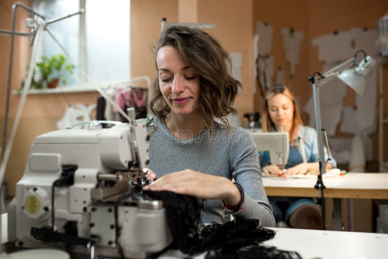 As costureiras das mulheres trabalham na oficina em máquinas de costura foto de stock As costureiras das mulheres trabalham na oficina em máquinas de costura foto de stock