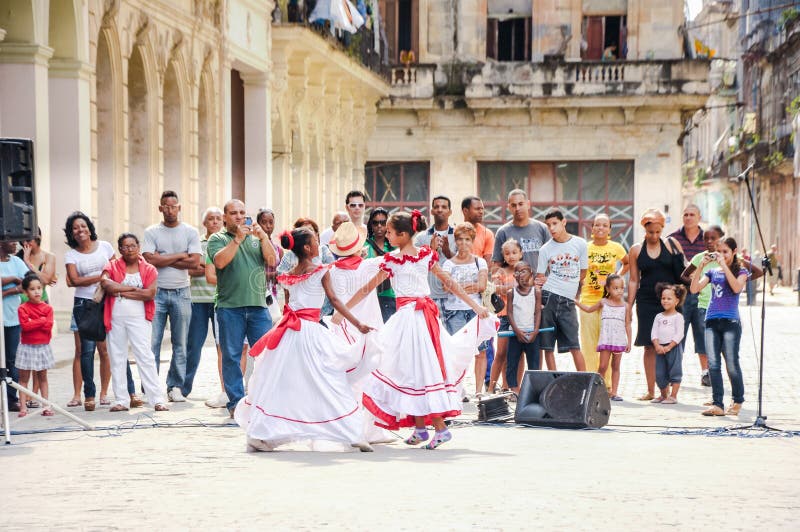 As crianças na roupa cubana tradicional executam na rua. 