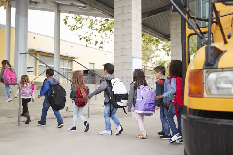 As crianças da escola primária chegam na escola do ônibus escolar